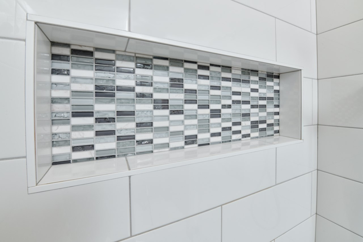 Bathroom tile niche featuring a modern mosaic design with gray, black, and white tiles, showcasing J.T. McDermott Remodeling Contractors' expertise in bathroom renovations.