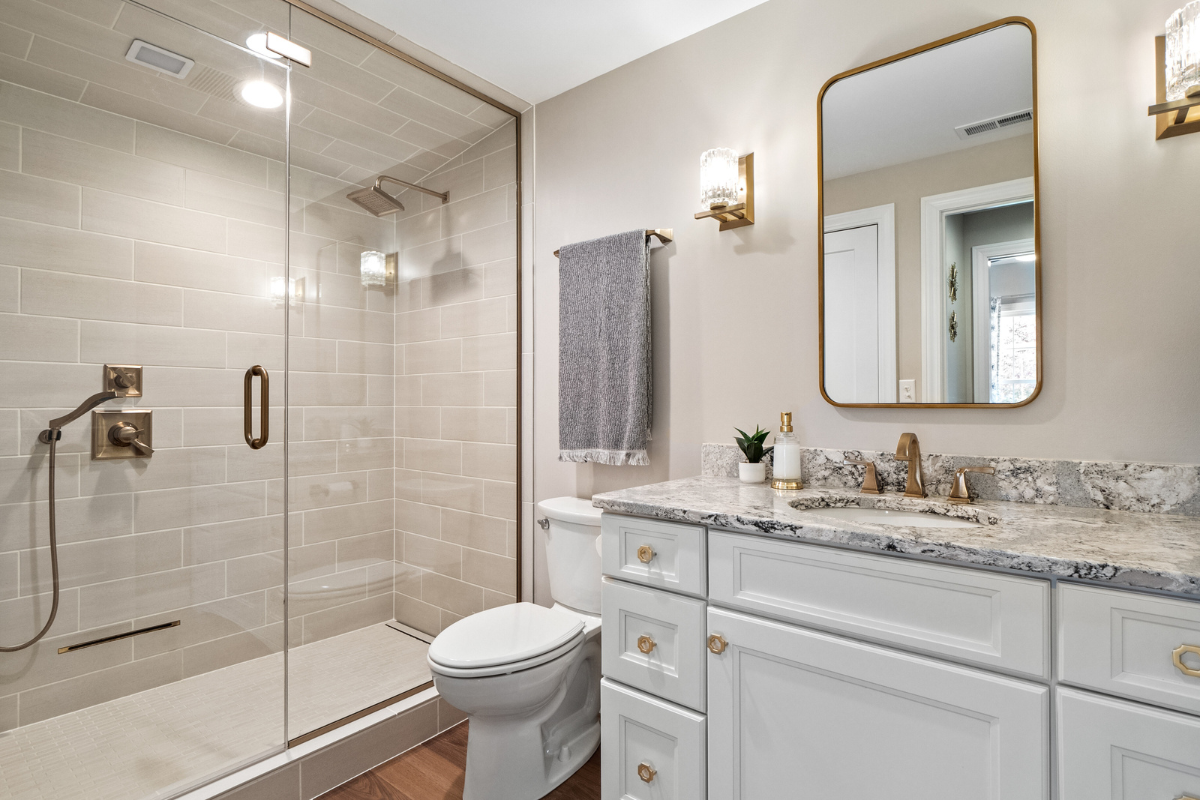 Modern bathroom interior featuring a glass shower enclosure, elegant fixtures, a white vanity with marble countertop, and stylish lighting, showcasing J.T. McDermott Remodeling Contractors' expertise in bathroom renovations.