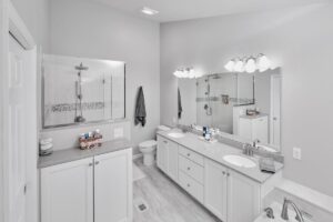 Large bathroom remodel with double vanity, white cabinetry, and full wall mirrors