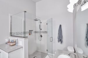 Contemporary bathroom remodel with frameless glass shower, white tile walls, and minimalist design